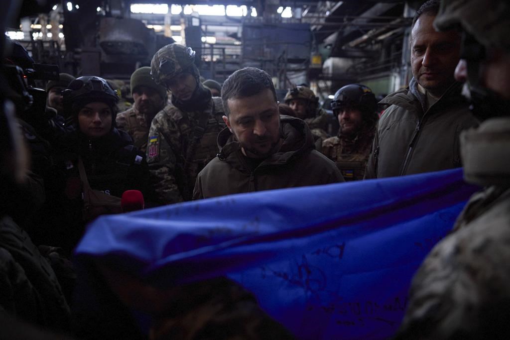 In this photo provided by the Ukrainian Presidential Press Office, Ukrainian President Volodymyr Zelenskyy, signs a Ukraine national flag, at the site of the heaviest battles with the Russian invaders in Bakhmut, Ukraine, Tuesday, Dec. 20, 2022. (Ukrainian Presidential Press Office via AP)