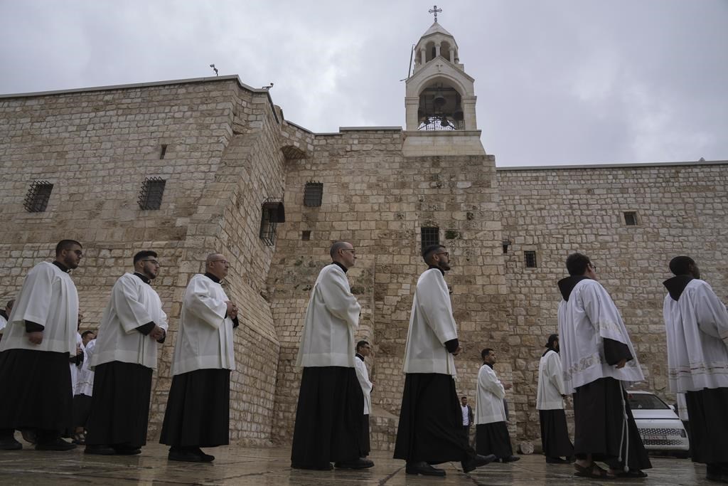 Le clergé catholique marche en procession à côté de l'église de la Nativité, traditionnellement considérée comme le lieu de naissance de Jésus, la veille de Noël, à Bethléem, en Cisjordanie, le dimanche 24 décembre 2023.