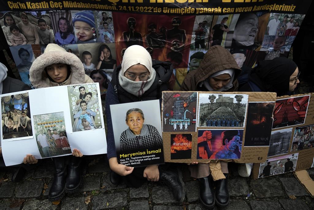 Women sit holding pictures of victims and posters reading "We have a funeral. Our hearts bleed. Urumqi (capital of China's Xinjiang region) is burning", in front of the Chinese consulate in Istanbul, Turkey, Wednesday, Nov. 30, 2022. MPs will vote this afternoon on whether to start a refugee program to resettle 10,000 Uyghurs fleeing persecution in China. THE CANADIAN PRESS- AP-Khalil Hamra