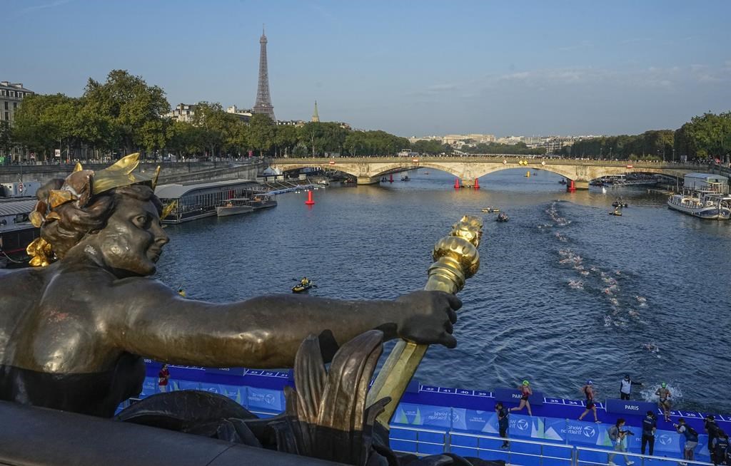 FILE - Athletes dive and swim in the Seine river from the Alexander III bridge on the first leg of the women's triathlon test event for the Paris 2024 Olympics Games in Paris, Thursday, Aug. 17, 2023. In 2024. Paris Olympics organizers and other officials cancelled paratriathlon swimming competition Saturday, Aug. 19, 2023, in the Seine River because of new concerns about water quality. The competition is a key test event ahead of the 2024 Summer Games. (AP Photo/Michel Euler, File)