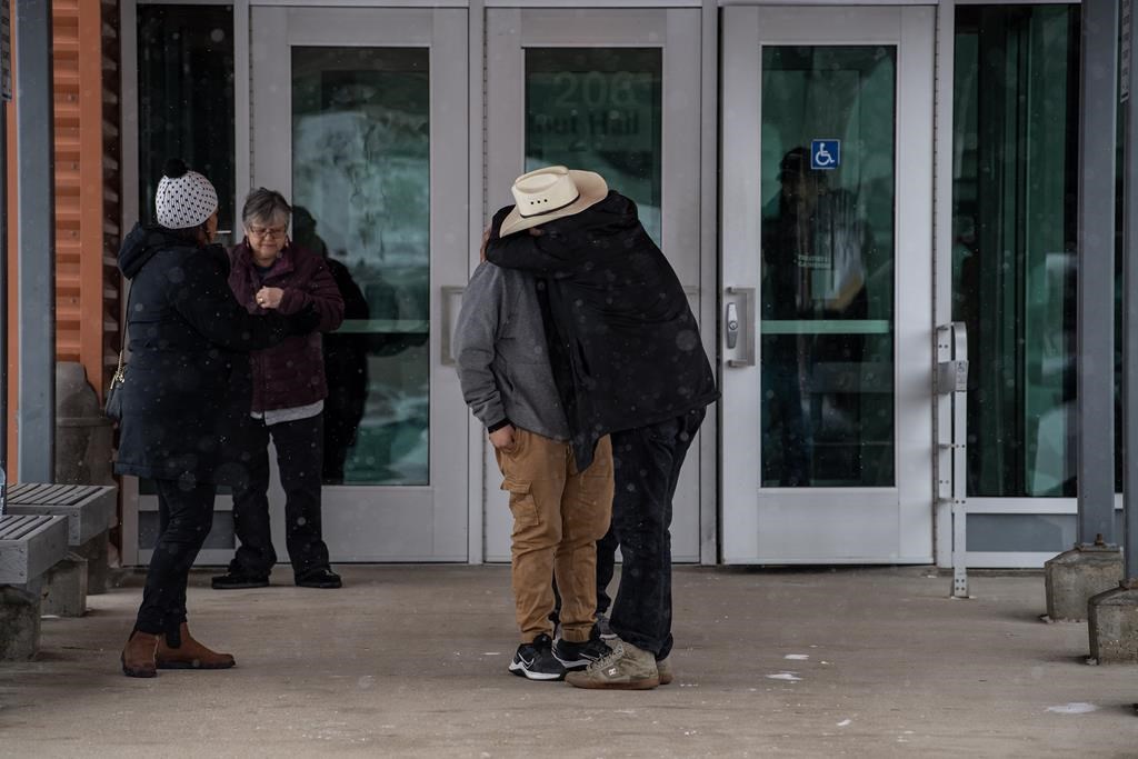 Les gens se réconfortent pendant une pause déjeuner lors de l'enquête du coroner public sur les agressions au couteau de masse survenues dans la Nation crie de James Smith en 2022 à Melfort, en Saskatchewan, le mardi 16 janvier 2024.