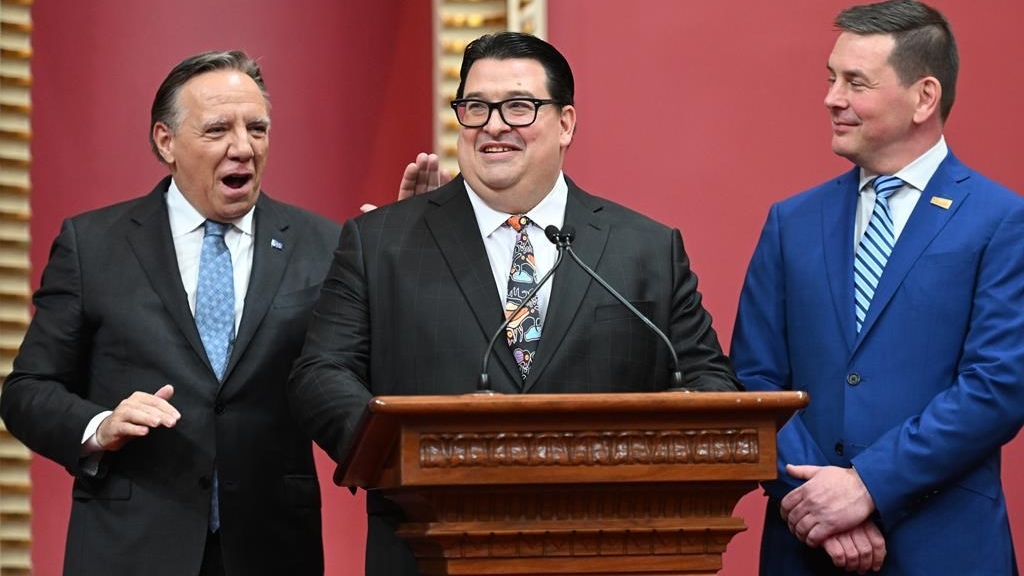 Sylvain Lévesque reçoit une tape dans le dos du premier ministre du Québec, François Legault, lors de son assermentation, le 18 octobre 2022, au cours d'une cérémonie à l'Assemblée législative de Québec.