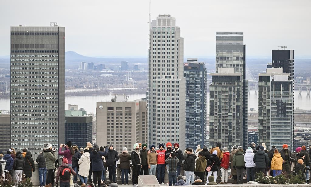 Des gens regardent l'horizon de Montréal depuis le parc du Mont-Royal le jour du Nouvel An à Montréal, le lundi 1er janvier 2024.