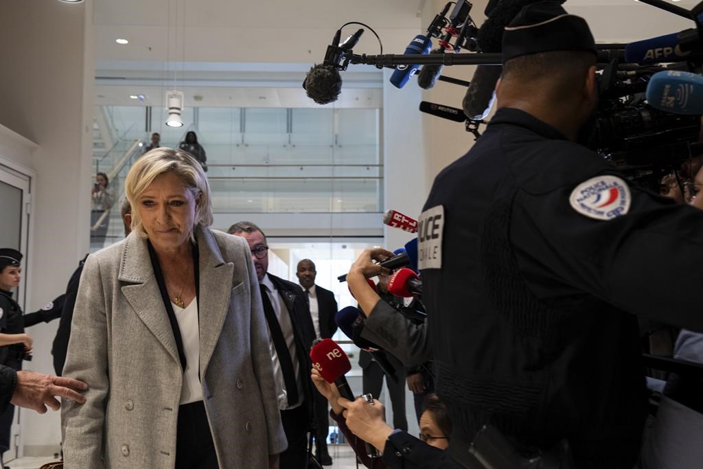 French far-right leader Marine Le Pen walks past the media as she arrives at the court house in Paris, Monday, Sept. 30, 2024. (AP Photo/Louise Delmotte)