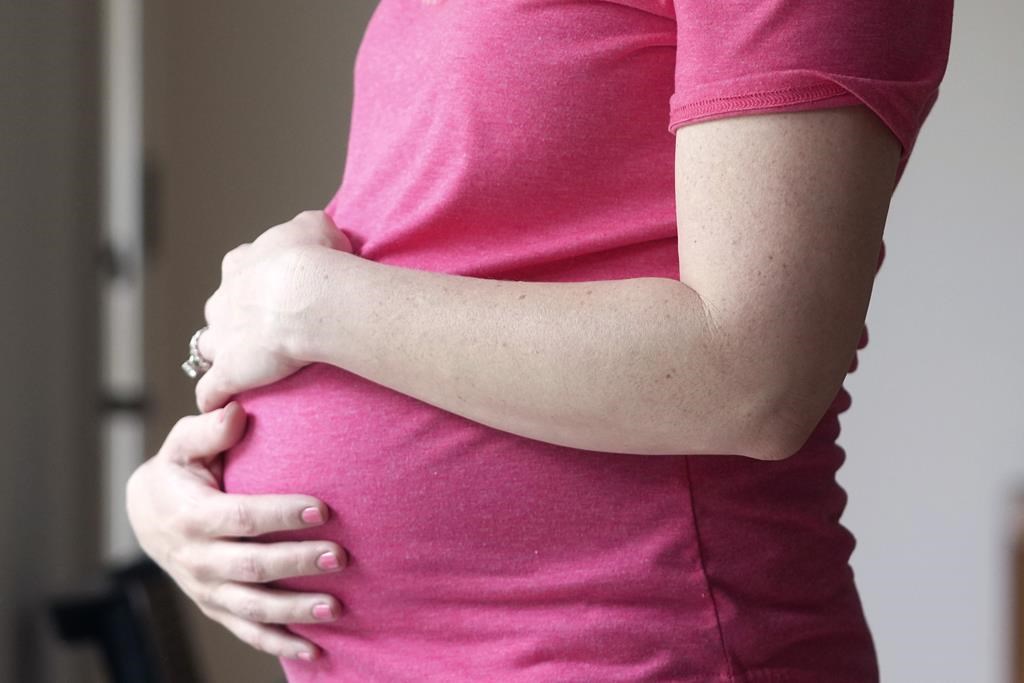 A pregnant woman stands for a portrait in Dallas, Thursday, May 18, 2023. A paper published in the Canadian Medical Association Journal says it's time to invest in early pregnancy assessment clinics that can provide proper care during and after a miscarriage, which can have devastating effects on patients. THE CANADIAN PRESS/AP, LM Otero