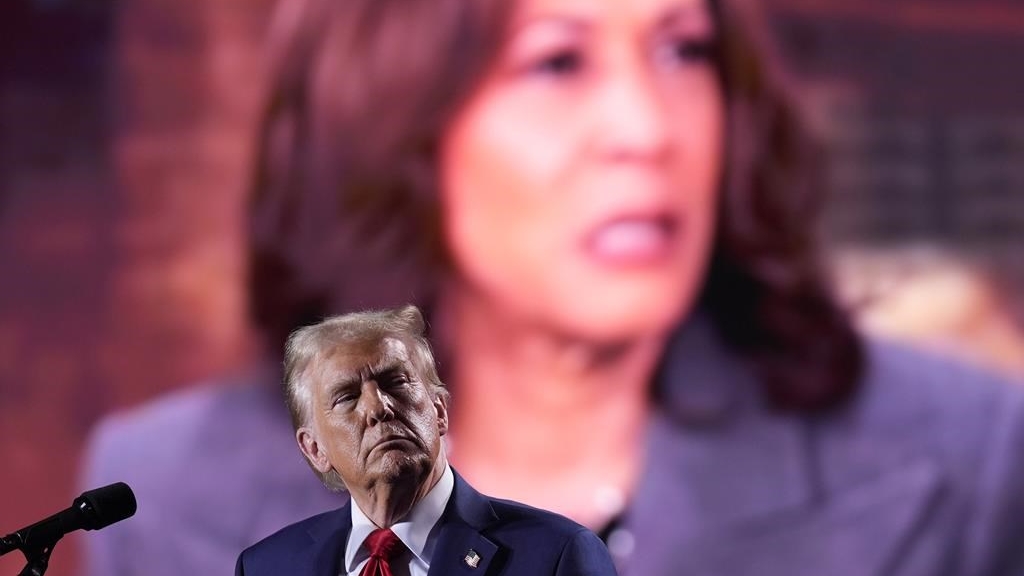 Republican presidential nominee former President Donald Trump watches as a video featuring Democratic presidential nominee Vice President Kamala Harris plays during a campaign event, October 18, 2024 in Detroit. THE CANADIAN PRESS/AP, Evan Vucci