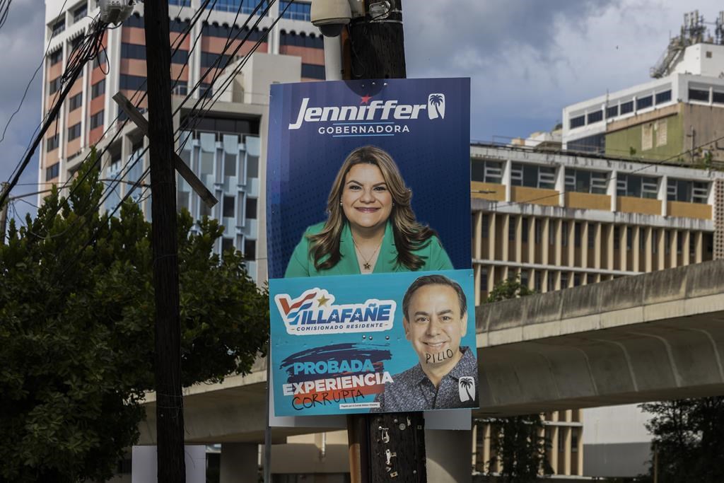 A campaign poster promotes New Progressive Party gubernatorial candidate and Puerto Rico’s representative in Congress Jenniffer González, above a campaign poster of resident commissioner candidate Luis Villafañe, defaced with the Spanish words for corrupt and rogue, in San Juan, Puerto Rico, Saturday, Nov. 2, 2024. (AP Photo/Alejandro Granadillo)