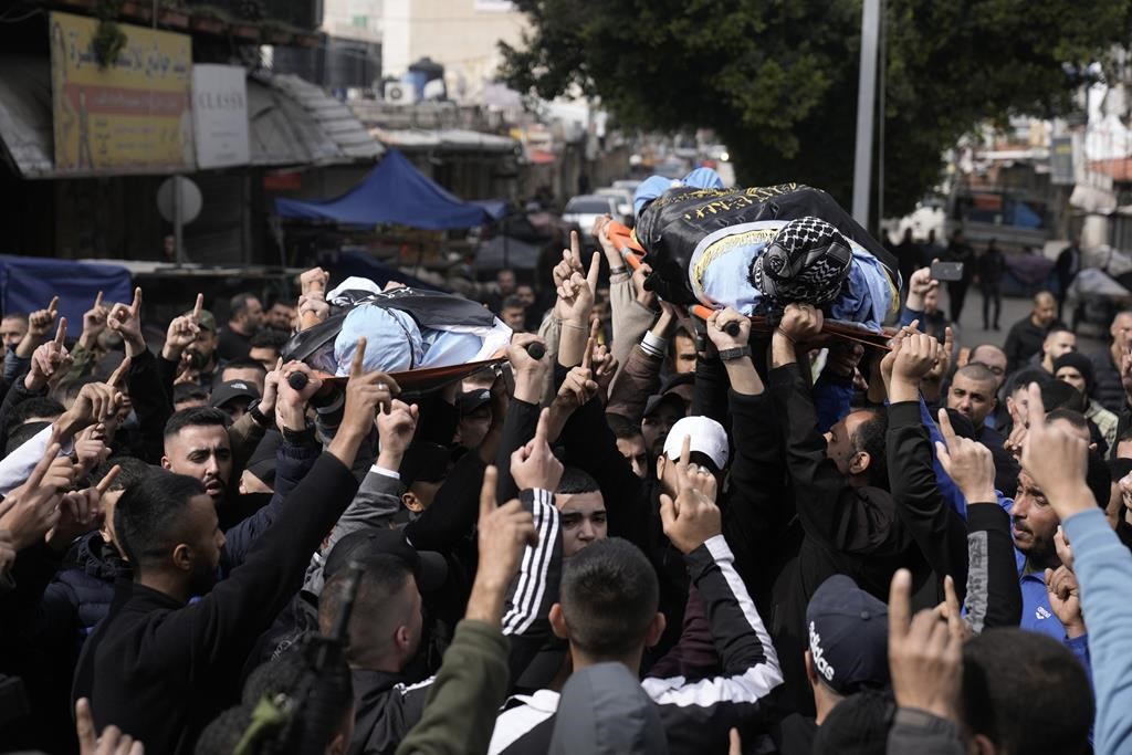 Gunmen carry the bodies of Said Jaradat, left, and Yasser Hanoun, both draped in the flag of the Islamic Jihad militant group, on Friday, Feb. 23, 2024. The pair were killed in an Israeli drone strike on a car in the West Bank Jenin refugee camp a day earlier. The Israeli military alleged that Hanoun was previously involved in several shooting attacks targeting Israeli settlements and army posts. (AP Photo/Majdi Mohammed)