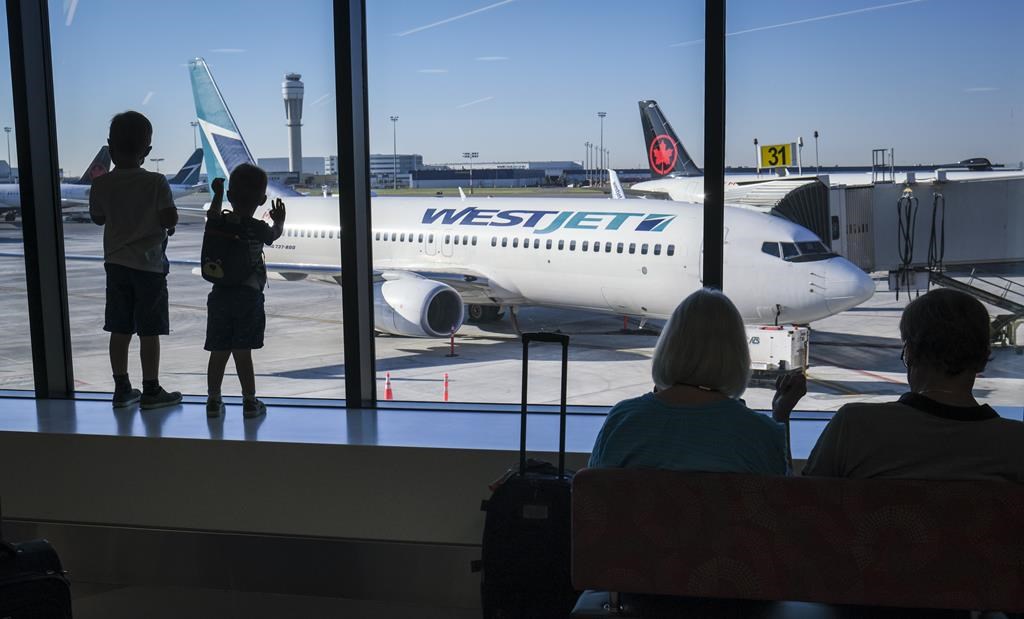 Young boys look out at Air Canada and WestJet planes at Calgary International Airport in Calgary on August 31, 2022. THE CANADIAN PRESS/Jeff McIntosh