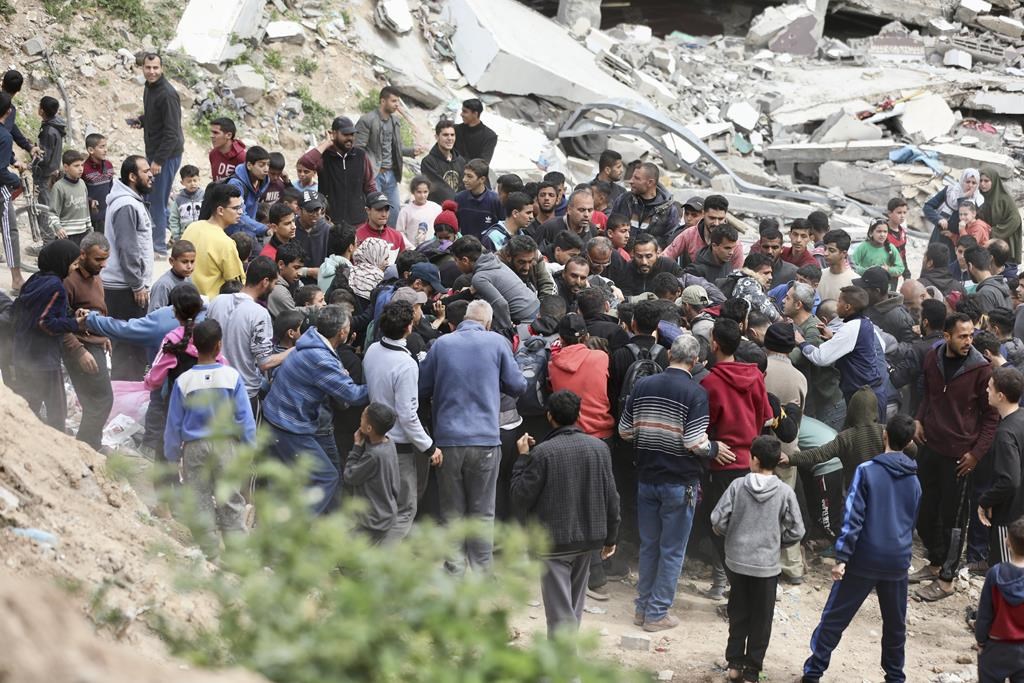 Palestinians rush to collect the humanitarian aid airdropped into Gaza City, Gaza Strip, on Sunday, March 17, 2024. (AP Photo/Mohammed Hajjar)