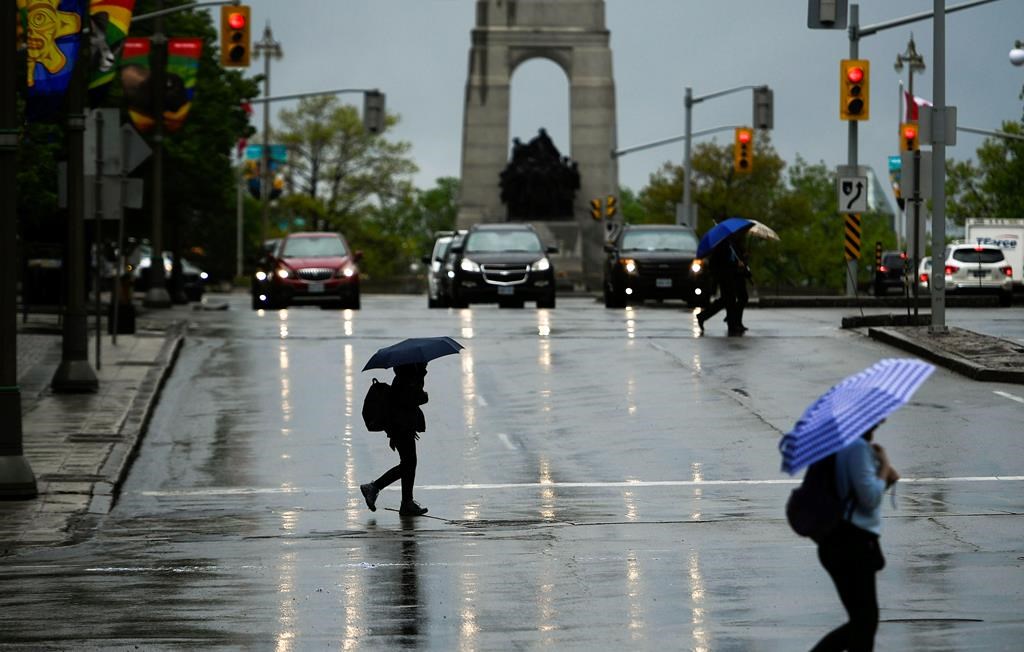 People cross Elgin Street as rain falls in Ottawa on Tuesday, May 17, 2022. As talks continue in the national capital on a global plastics treaty, a new report says more than 1,000 kilograms of microscopic plastic particles will fall on the national capital throughout a single day. THE CANADIAN PRESS/Justin Tang