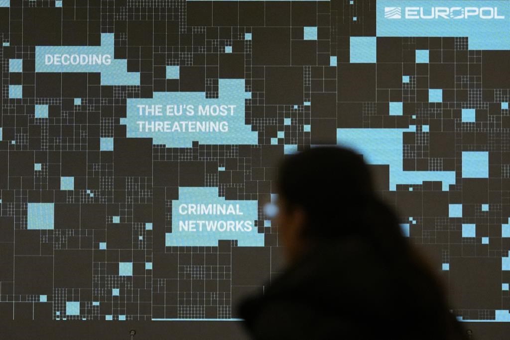 A woman walks by a projection prior to a media conference to present the findings of Europol's report on the most threatening criminal networks in the European Union, at the Residence Palace in Brussels, Friday, April 5, 2024. (AP Photo/Virginia Mayo)
