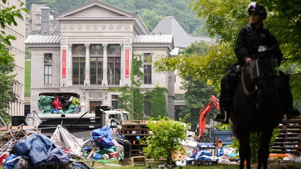 Une pelleteuse vide des tentes dans une benne à ordures lors du démantèlement d'un campement pro-palestinien à l'Université McGill à Montréal, le 10 juillet 2024