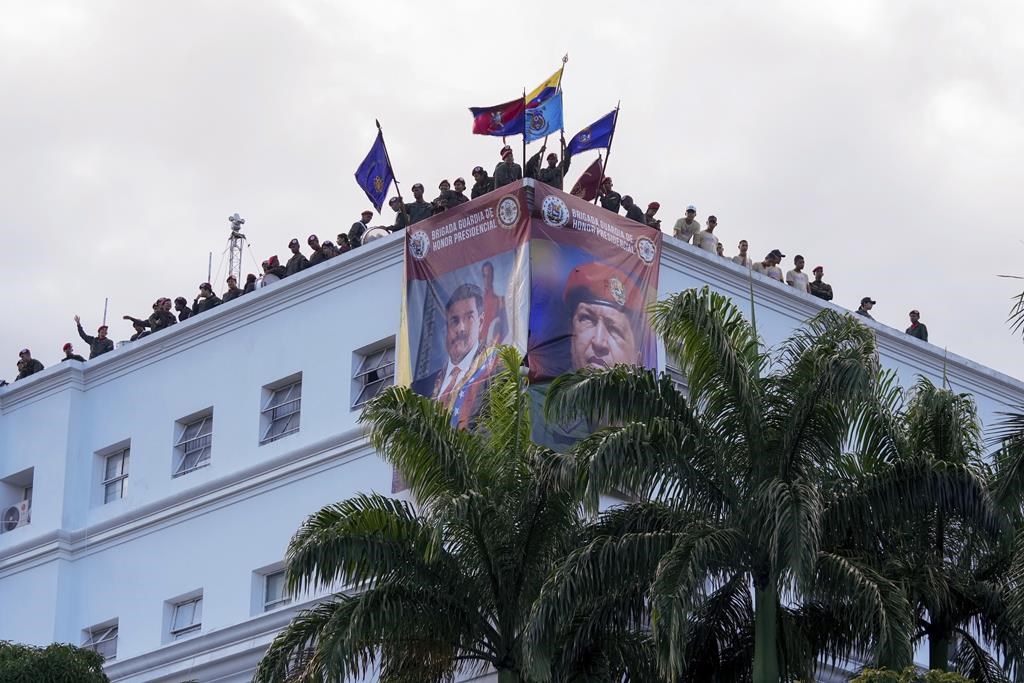 Des membres de la garde présidentielle agitent des drapeaux depuis le quartier général du régiment lors d'un rassemblement de partisans du gouvernement en faveur de la réélection du président Nicolas Maduro à Caracas, au Venezuela, le mardi 30 juillet 2024.