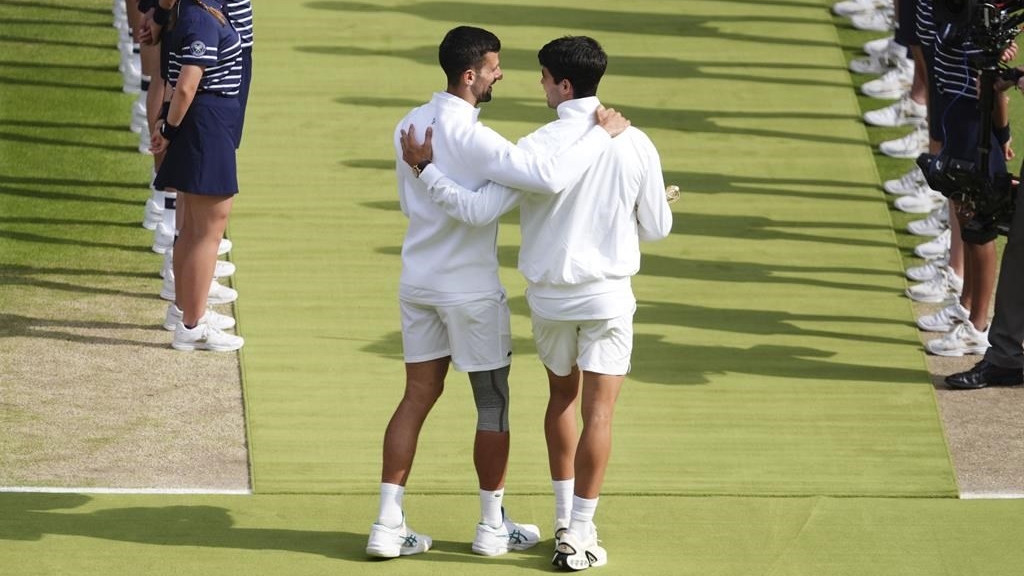 L'Espagnol Carlos Alcaraz discute avec le Serbe Novak Djokovic après la finale masculine du tournoi de Wimbledon, le 14 juillet 2024. 