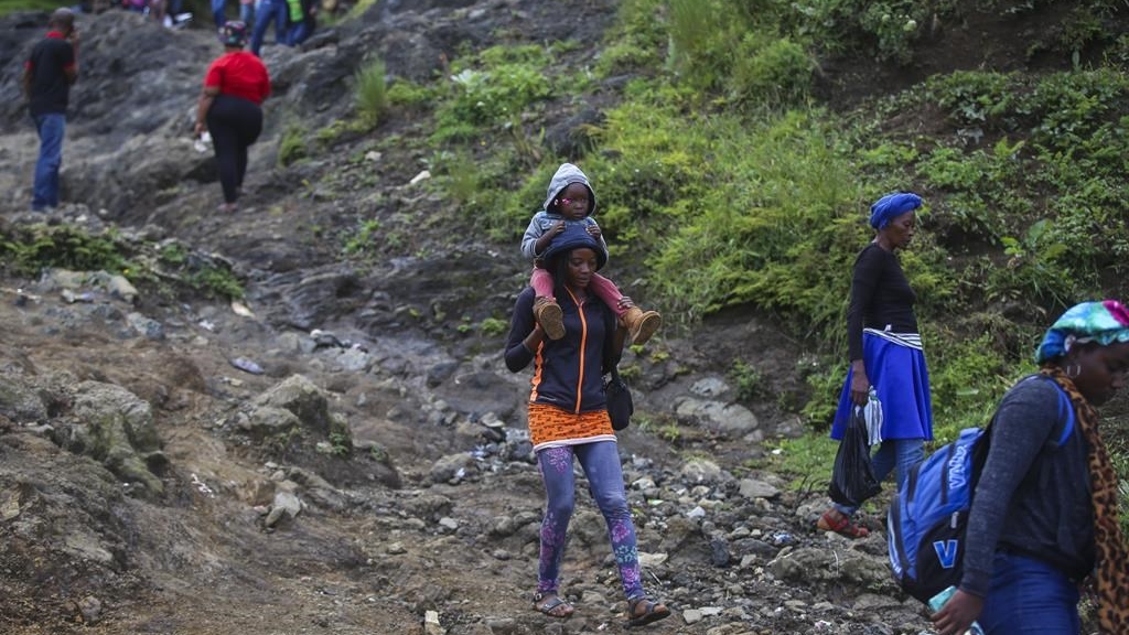 Une femme porte un enfant sur ses épaules alors qu'elle traverse les montagnes pour éviter la violence des gangs criminels dans le faubourg de Kenscoff à Port-au-Prince, en Haïti, le mardi 10 septembre 2024.