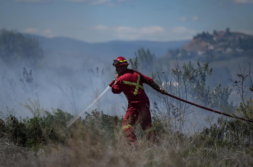 Une partie d'une communauté de l'intérieur de la Colombie-Britannique fait l'objet d'une évacuation tactique en raison de la menace d'un incendie de forêt à proximité. Un pompier dirige de l'eau sur un feu d'herbe qui brûle à Kamloops, en Colombie-Britannique, le lundi 5 juin 2023. 